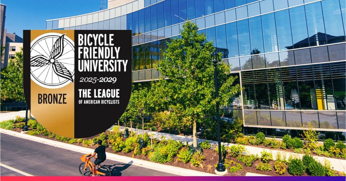 Student with Bicycle in front of Hall of Science with Badge Overlay for Bicycle Friendly University 2025-2029 Award