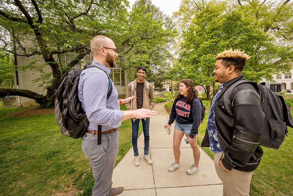 A group of students speaking with a faculty member on campus