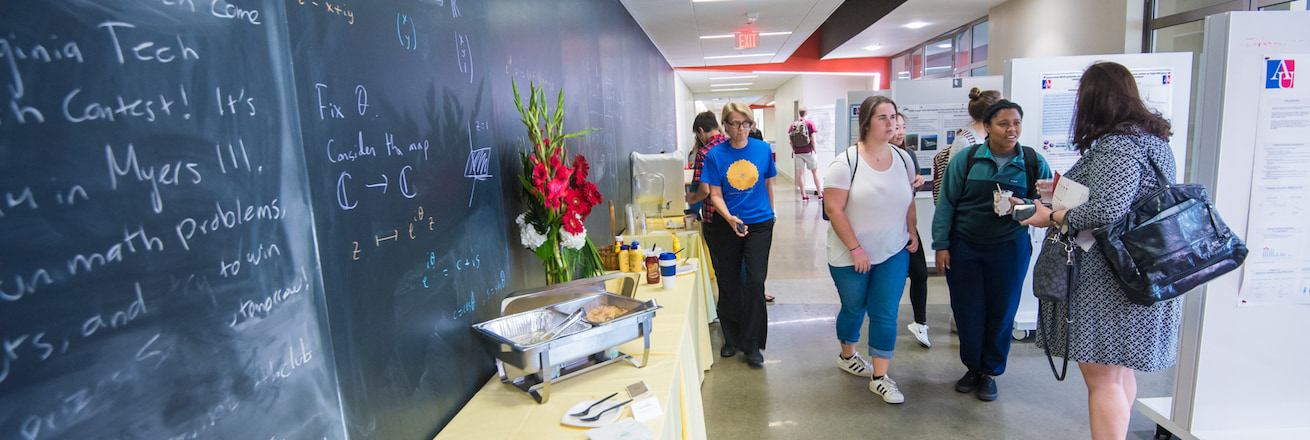 Chalkboard, food setting, and people talking in Don Myers hallway.