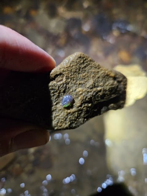 Fingers holding rock sample.