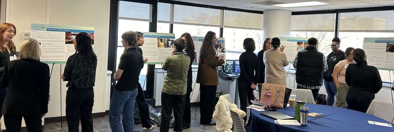 Poster session at AU with groups in discussion with presenters.