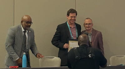 Dr. Herr receiving award at ceremonial table from Dr. Safren.