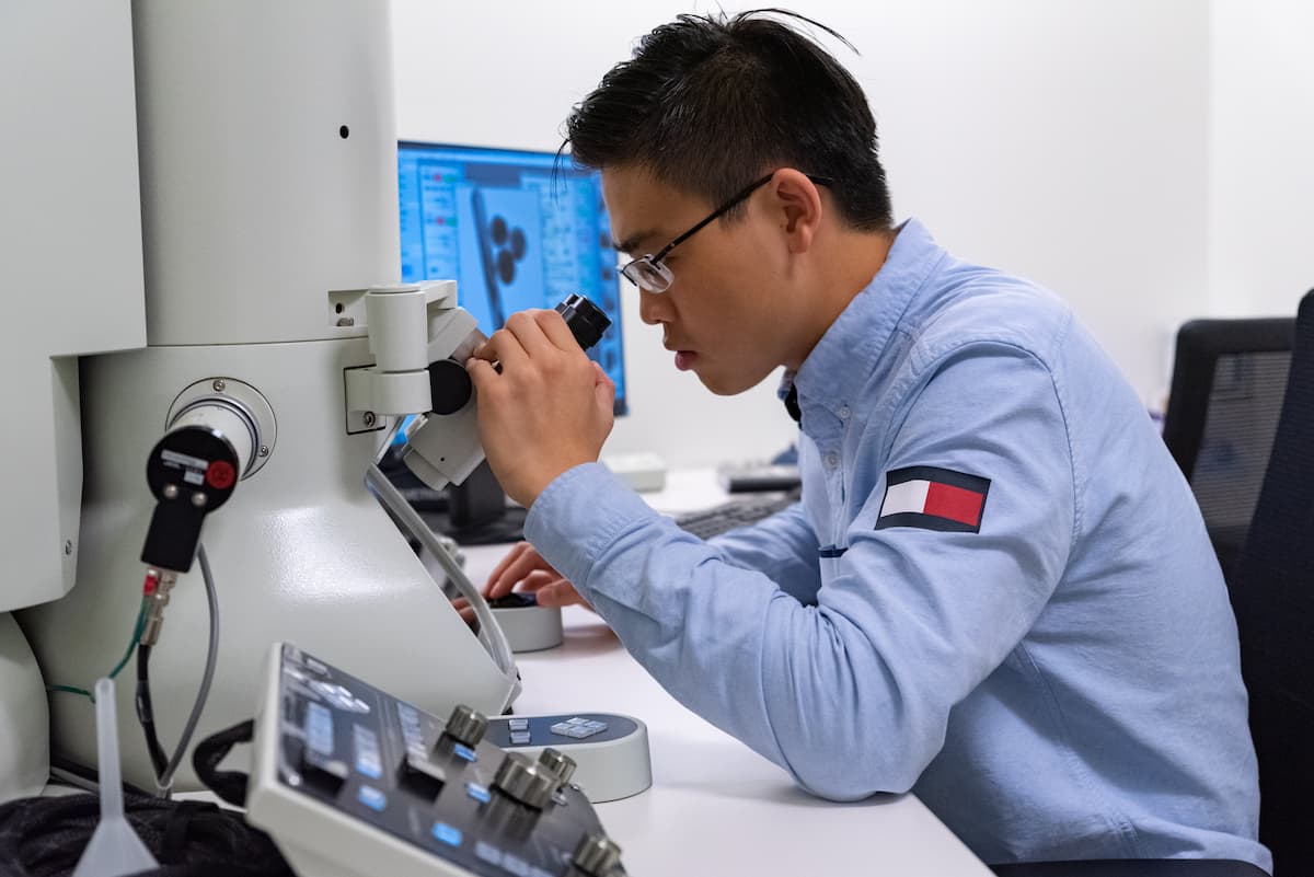 Student looking through viewfinder of JEOL Electron Microscope.