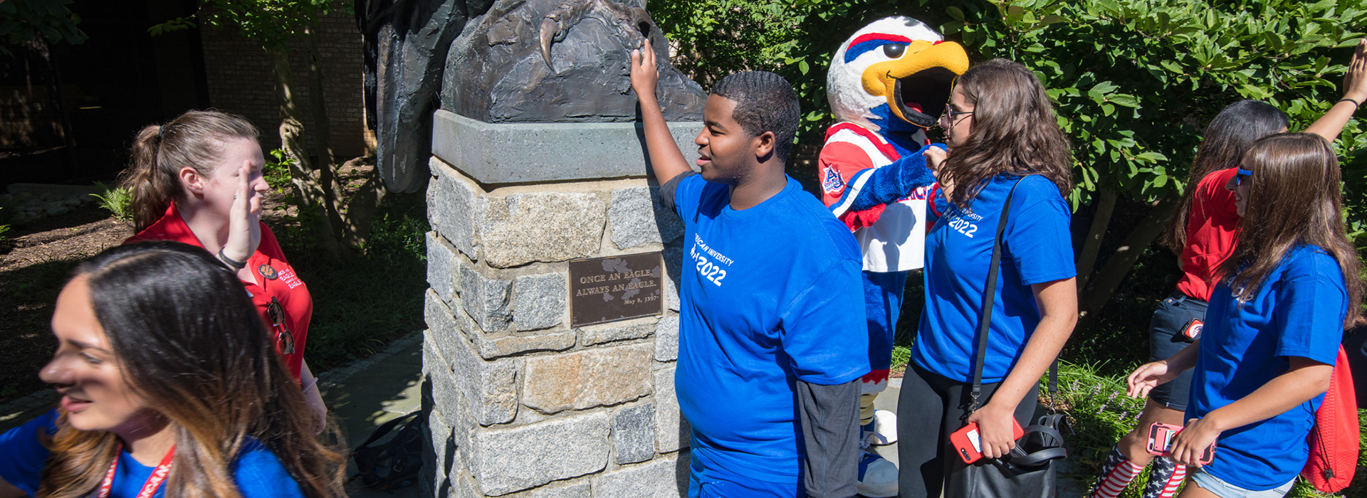 Panorama of students near a bronze eagle