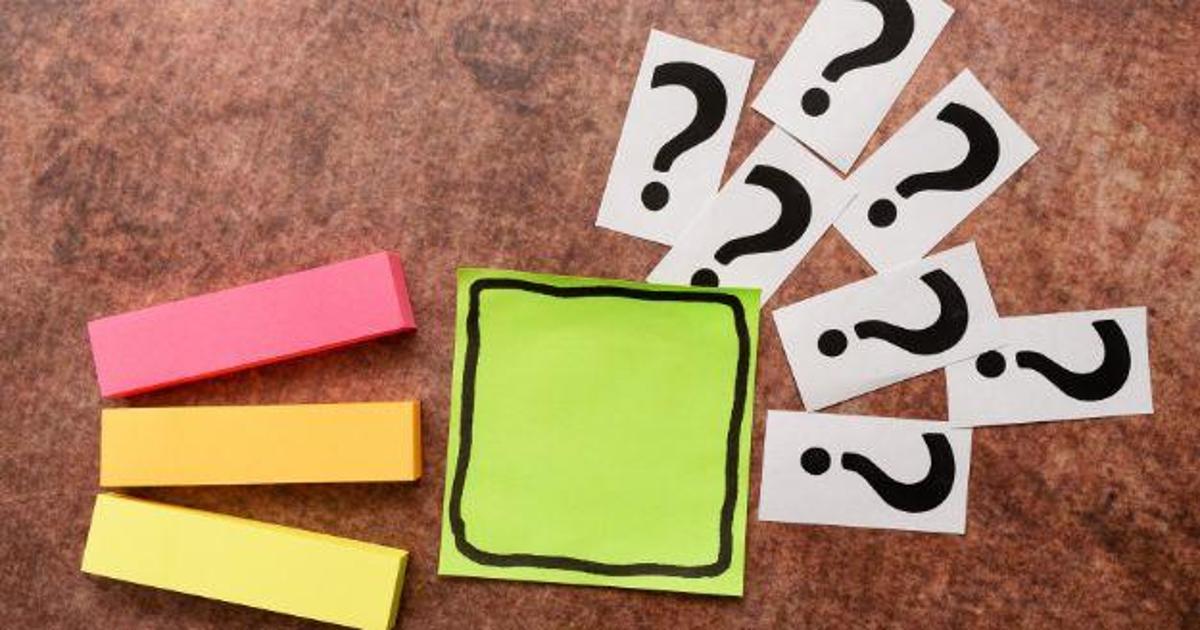 post-it notes and question marks on a wooden table
