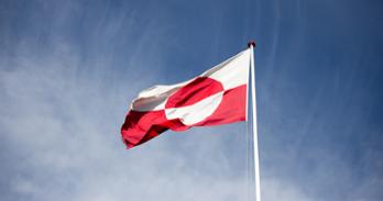 The flag of Greenland flies in a blue sky