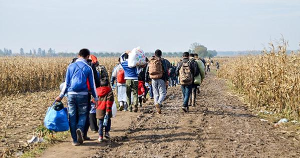 Refugees and migrants walking on fields. Group of refugees from Syria, Iraq and Afghanistan on their way to European union. Balkan route.