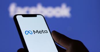 A person holds a phone that shows the Meta logo on screen