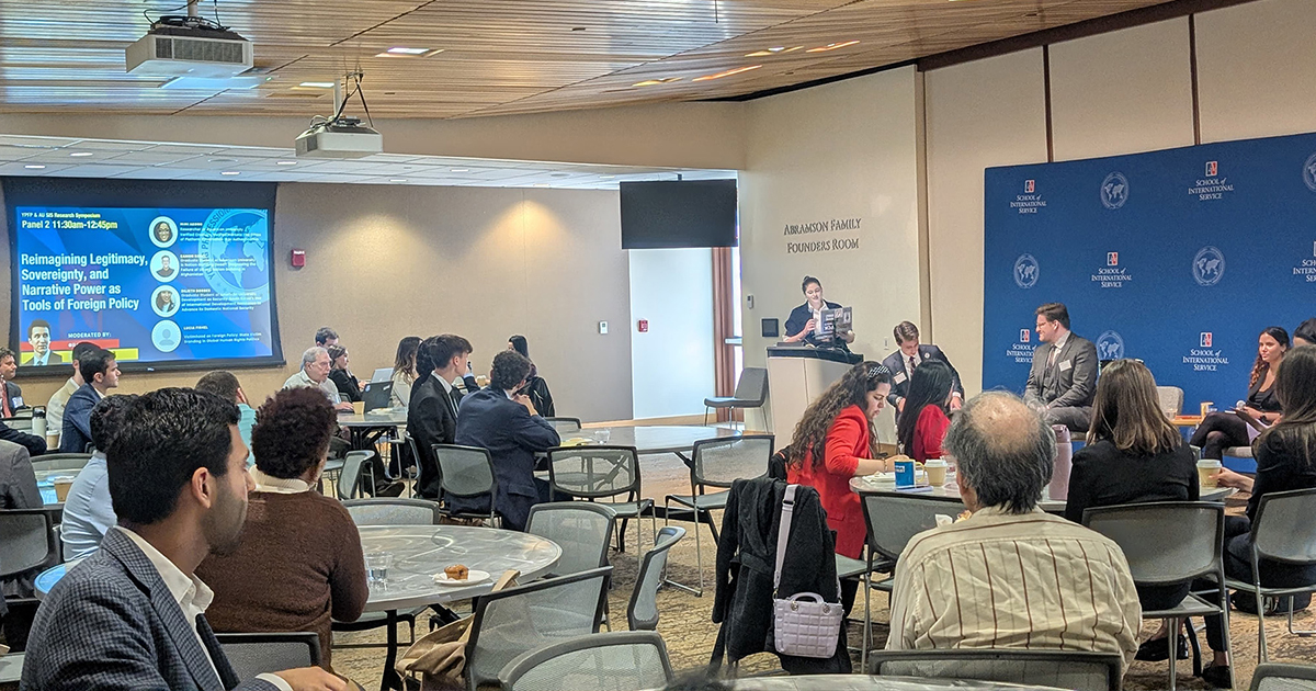 Attendees at tables look toward a speaker at the podium.