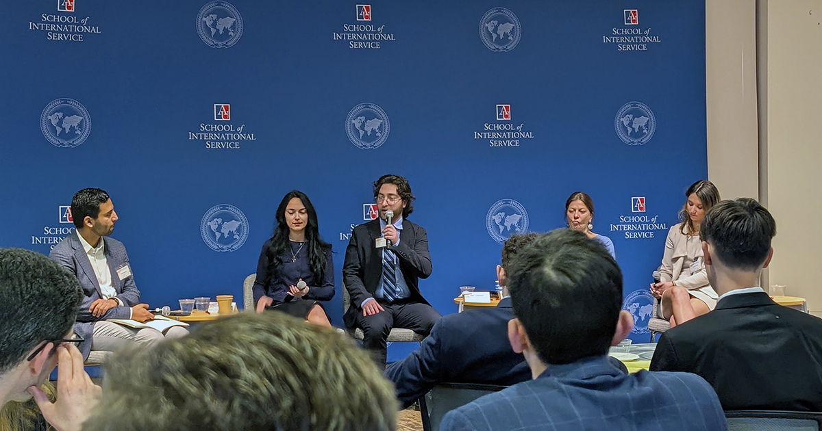 A panel speaker on stage speaking into a microphone.