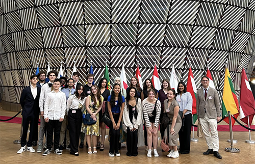Global scholars students pose in DC building with different country flags behind them
