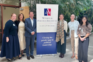 six people standing near a banner at american university