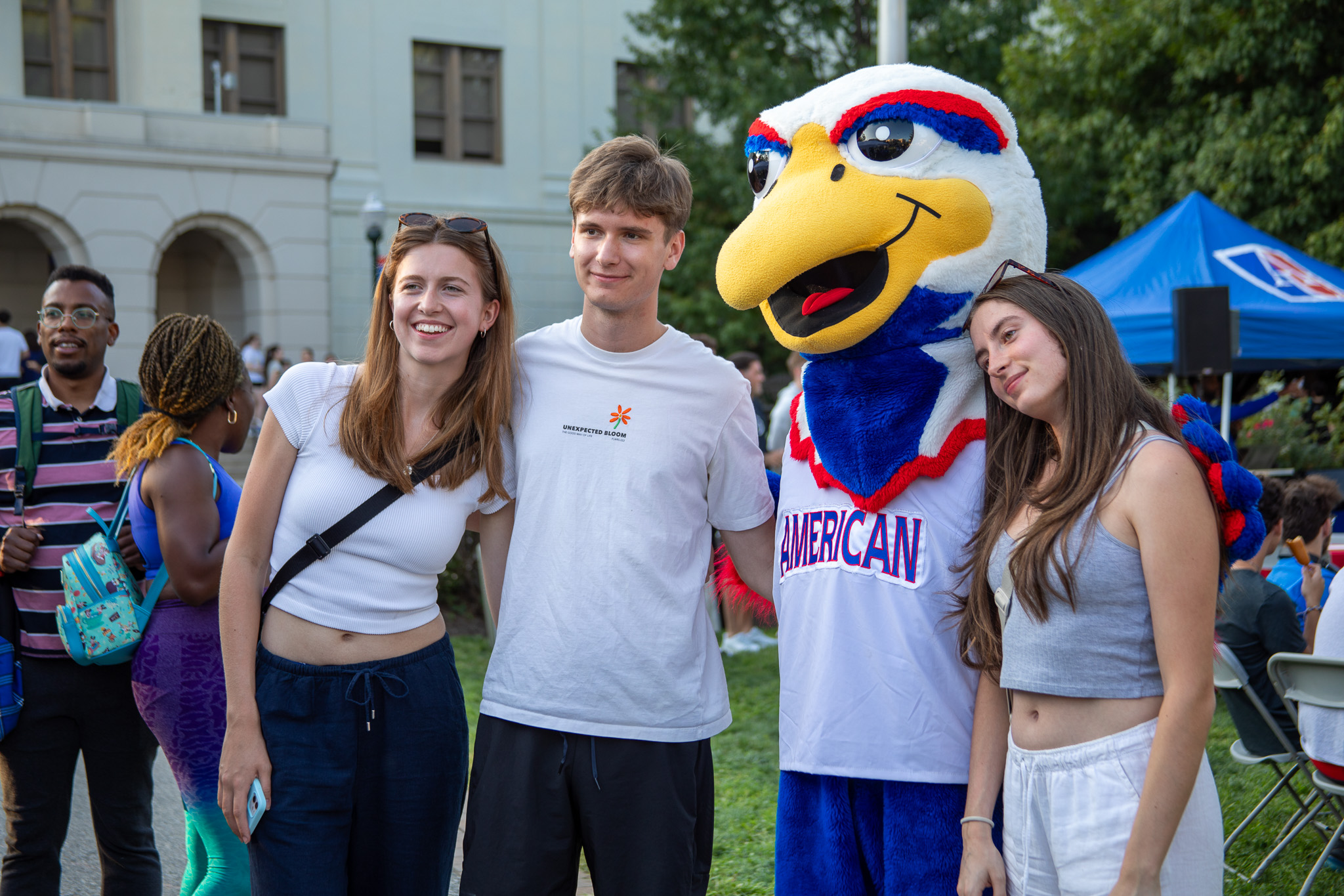 AU mascot Clawed poses with three students for a picture.